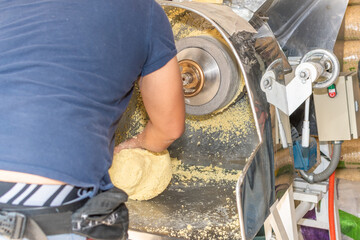 front view of a nixtamal mill while a man takes out the dough that is being produced