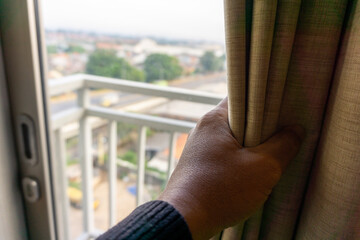 the hand opens the window curtain from left to right