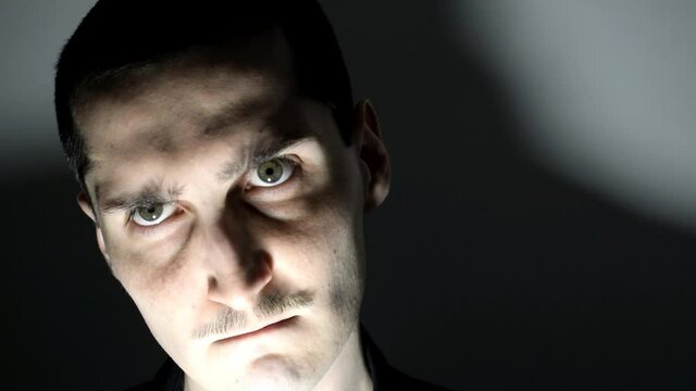 Angry sinister man in the darkness staring at the camera