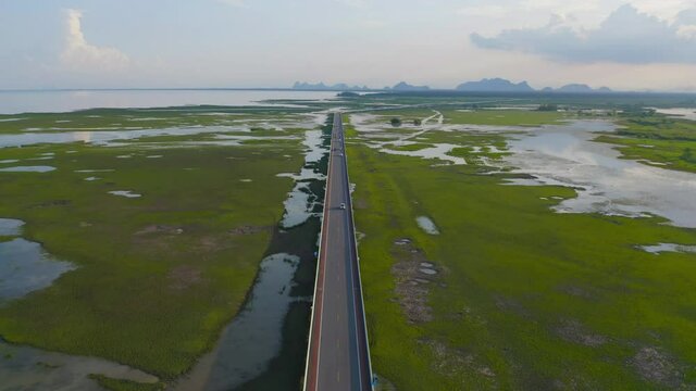 Aerial view of street road highway with swamp or lagoon in Phang Nga Bay, lake, sea or river in national park and mountain or hill in Thailand. Natural landscape background.