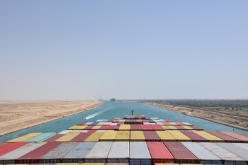 View on the containers loaded on deck of cargo ship. Vessel is transiting Suez Canal on her international trade route. Suez canal landscape.