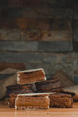 
Stack of Alfajores with lots of dulce de leche seen from the front. Stone bottom and wooden base