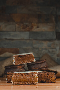 
Stack Of Alfajores With Lots Of Dulce De Leche Seen From The Front. Stone Bottom And Wooden Base