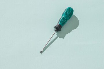 Manual screwdriver for cross-shaped screws on a light background.