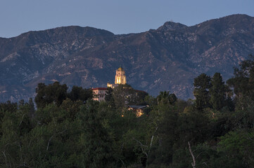 Fototapeta na wymiar This image shows the landmark Richard Chambers Courthouse building in Pasadena towering over the trees along the Arroyo Seco. The San Gabriel Mountains are in the background.
