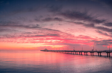 Naklejka na ściany i meble Beautiful Panoramic Seaside Sunrise with Dramatic Sky and Pier