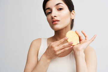 Beautiful brunette holding a sponge in her hands clean health skin close-up