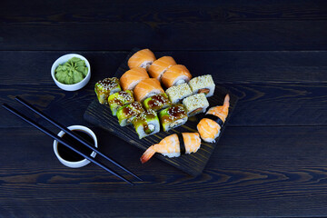 Assorted japanese sushi food on a dark wooden background. Sushi roll Philadelphia with salmon, Sushi roll Maki with eel, avocado and shrimp sushi.