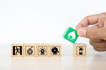 Close-up hand choose wooden toy blocks stacked with fire prevent icon with door exit sing or escape...