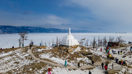 Tourists Circle Around All Auspicious Stupa of Great Awakening at Ogoy Island, Baikal Lake, Russia in Winter. Aerial View