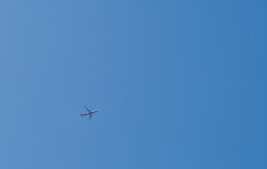 Airliner flying high above in clear blue sky.