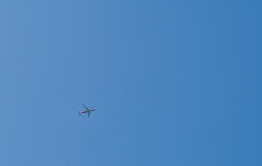 Airliner flying high above in clear blue sky.