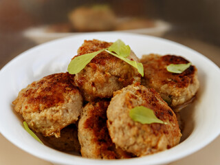 Cutlets decorated with lettuce leaves in white plate are reflected in mirror in background