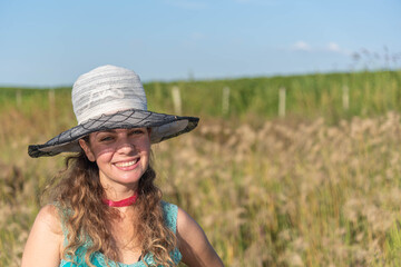 Blonde woman wearing a hat in a farm area and in the background a soy plantation