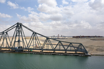 Fototapeta na wymiar Landscape of Suez Canal, view from transiting cargo ship. Bridge construction on the Canal bank. 