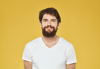 Fototapeta premium Brunette man on a yellow background in a white t-shirt cropped view