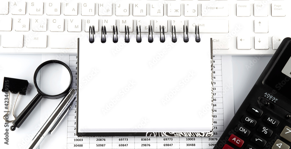 Poster opened notebook and other office equipment such as computer keyboard on office desk.