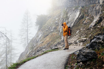 Man with backpack hiking in foggy woodland and rocky mountains in Austria