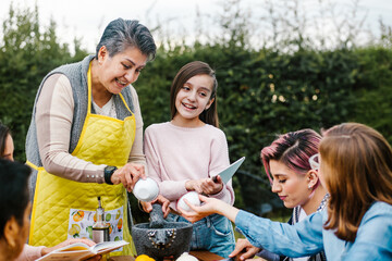 latin grandmother and granddaughter, daughter cooking mexican food at home, three generations of women in Mexico