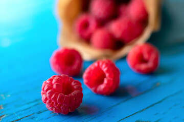 Raspberries macro photo on wooden blue painted surface on summer daylight