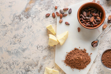 Cacao powder with beans and butter on grey background