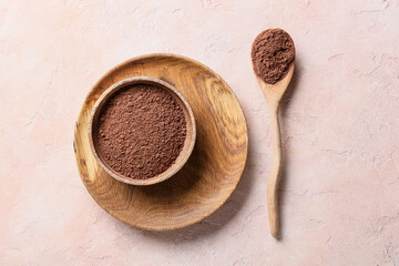 Plate and spoon with cacao powder on color background