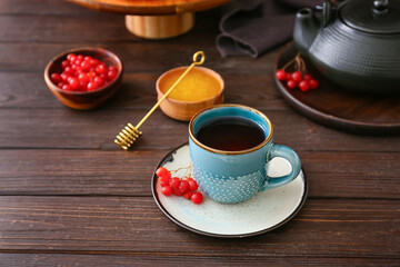 Cup of healthy viburnum tea and honey on table