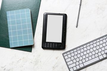 E-reader, computer keyboard and notebooks on light background