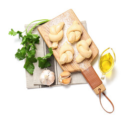 Board with uncooked garlic buns on white background