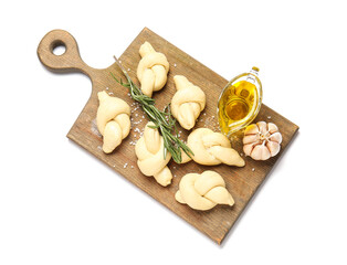 Board with uncooked garlic buns on white background