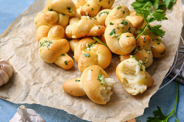 Parchment with tasty garlic buns on color background, closeup