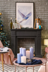 Table with burning candles in interior of living room decorated for Christmas