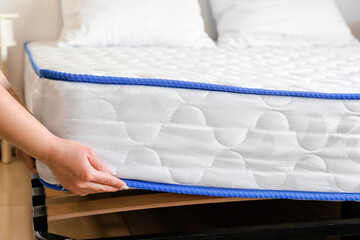 Woman putting soft orthopedic mattress on bed