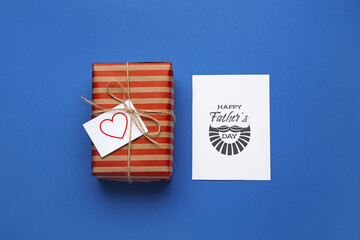 Gift box and greeting card for Father's Day celebration on color background
