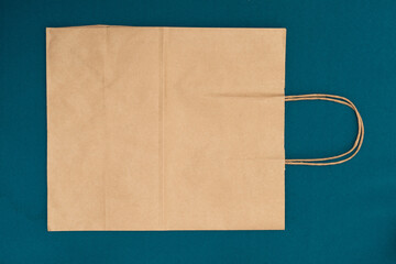 Paper bag on a blue background, brown shopping bag. Craft bag with handle. Packaging template mockup. Delivery service concept. Copy space