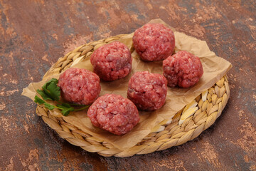 Raw meatball over wooden background