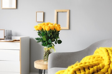 Vase with beautiful yellow roses on table in interior of room