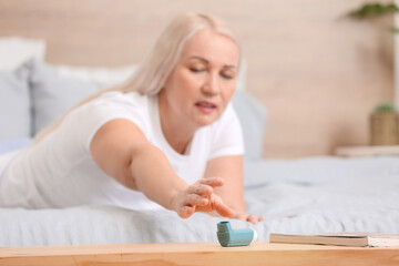 Mature woman taking inhaler from table