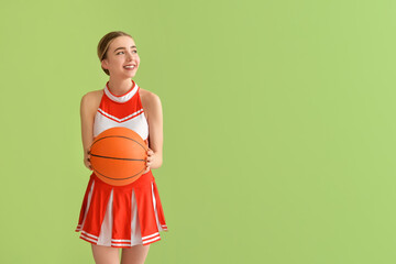 Beautiful cheerleader with ball on color background