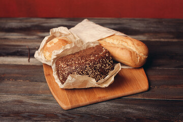 flour products baked loaf of bread on wooden board and red background in the background