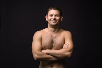 Fototapeta premium Handsome smiling man on the black background. Muscular and athletic. Man portrait. Male model in studio