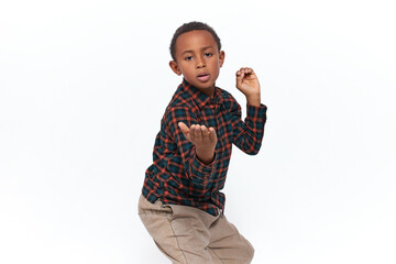 Studio image of handsome confident violent little Afro American boy posing isolated making kung fu...