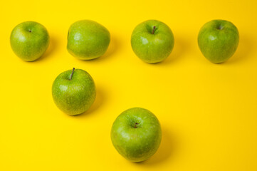 Large green apples, ripe and juicy. Photographed against a uniform yellow background.