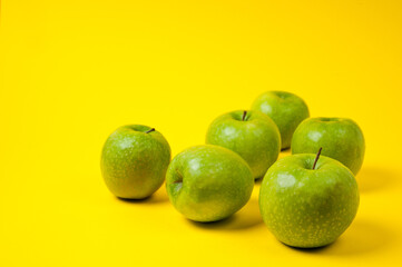 Large green apples, ripe and juicy. Photographed against a uniform yellow background.