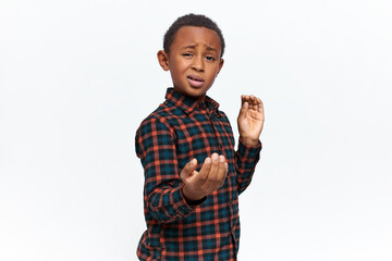 Isolated shot of confident self assured African schoolboy showing confidence and readiness to defend himself, making martial stance, posing against white blank wall background, mocking at his enemy