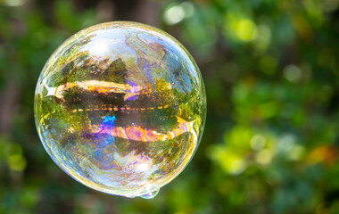 A large soap bubble flies in the park.