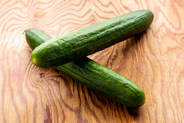 two green cucumbers on the wooden surface of the table