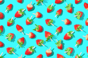 Juicy strawberries on a stick on a bright blue background with sharp shadows.