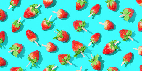 Juicy strawberries on a stick on a bright blue background with sharp shadows.