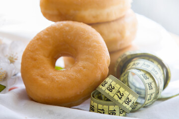 donuts or industrial pastries and measuring tape, diet and food concept